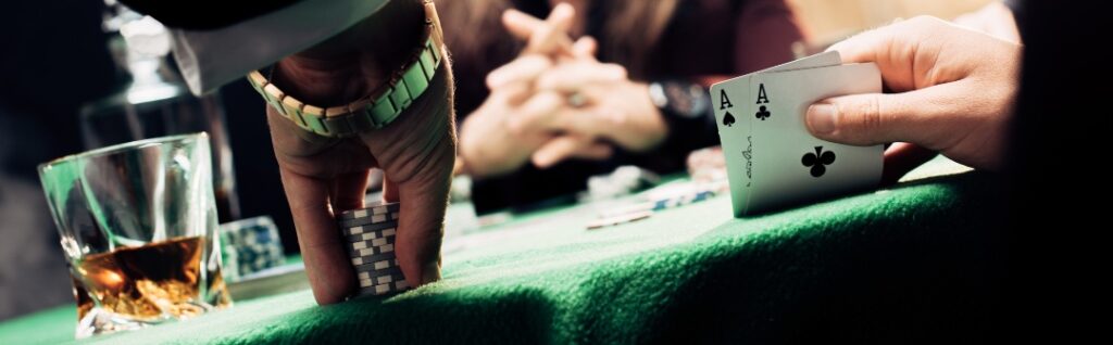 panoramic shot of man I Casino Monte Carlo touching playing cards and poker chips near player