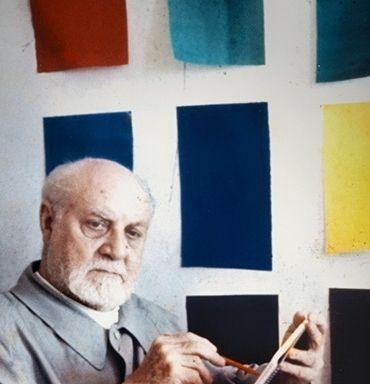Henri Matisse posing in his studio in front of one of his paintings